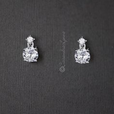 two pairs of diamond earrings sitting on top of a black surface