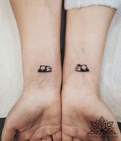 two small black cats on their hands tattooing each other's wrist tattoos for couples