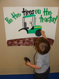 a young boy is painting a sign on the wall that says run the tires on the tractor