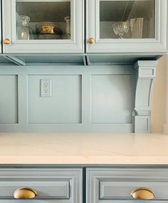 the cabinets are painted blue and have gold handles on each one side, along with marble counter tops