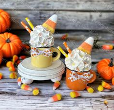 two cups filled with whipped cream and candy corn on top of an orange saucer