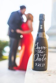 a bottle of save the date wine sitting on top of a table next to a man and woman