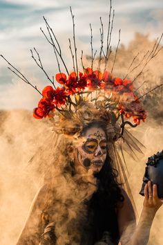 a woman with makeup and flowers on her head holding a vase in front of her face