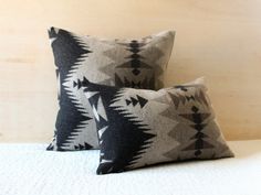 two black and white pillows sitting on top of a bed