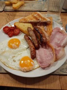 a white plate topped with bacon, eggs and toast on top of a wooden table