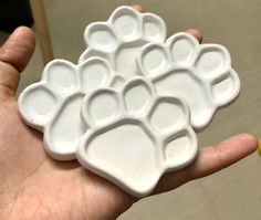 a person holding a white plate with paw prints on it's side in their hand