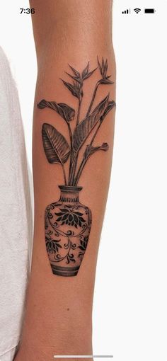 a black and white photo of a vase with plants in it on the arm tattoo