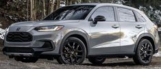 the front end of a silver 2020 honda passport parked on a dirt road with trees in the background