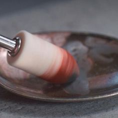 an object is being held in the middle of a metal plate on top of a table