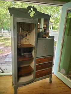 an old fashioned cabinet is in the middle of a room with wood floors and green walls