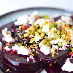 beets with goat cheese and pistachio toppings on a white plate, ready to be eaten