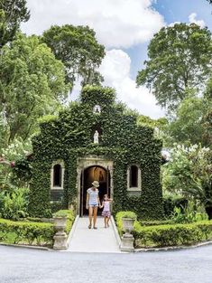 two people standing in front of a house covered in ivy