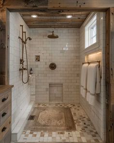 a bathroom with white tile and wood accents on the walls, along with an open shower