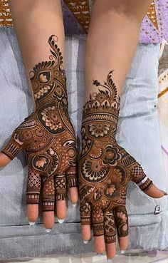 two hands with henna tattoos on them