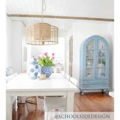 a white table with blue vases and flowers on it in a room that has wood floors