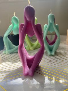 three candles sitting on top of a table in the shape of people with arms and legs