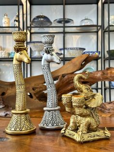 two gold and silver figurines sitting on top of a wooden table next to each other