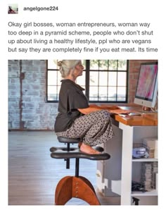 a woman sitting at a computer desk with her feet up on the chair and legs down