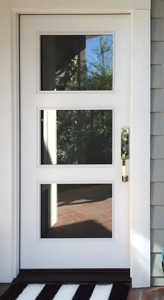 a white door with three panes of glass in front of it and a black and white rug on the floor