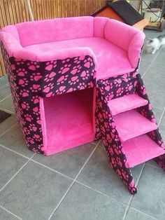 a pink and black cat bed with stairs on the floor next to a dog house