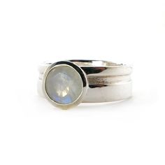 This gorgeous moonstone is set in a wide band with a cut out decorative element that goes all the way round the band. The same cut out also features on the bezel. The 6mm round moonstone is bezel set on a 6mm wide sterling silver band.The simplicity of this ring, matched with the blue rainbow hues of the moonstone, makes it a perfect piece to add to your collection.I can add engraving to the inside of the ring, like a date, or name. It is an additional $20, if you would like this, please choose Modern Silver Stackable Rings With Smooth Bezel, Anniversary Moonstone Ring With Bezel Setting, Modern Round Moonstone Rings, Modern Opal Ring With Bezel Setting, Modern Stackable Moonstone Ring, Minimalist Silver Moonstone Ring With Polished Finish, Modern Moonstone Wedding Ring With Bezel Setting, Silver Solitaire Moonstone Ring Round Cut, Modern Stackable Moonstone Ring For Anniversary