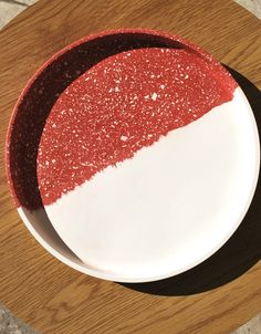 a red and white plate sitting on top of a wooden table