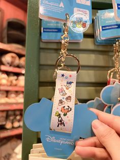 a person holding up a mickey mouse keychain in front of some other items