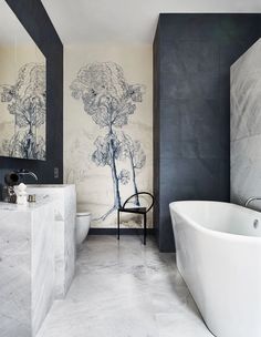 a bathroom with a large white bath tub sitting next to a wall mounted art piece