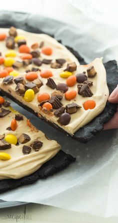 a person holding a piece of cake with candy and candies on it's crust