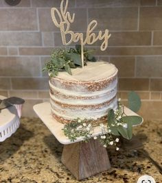 a cake with greenery on top sitting on a counter next to a brick wall