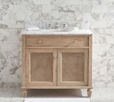 a bathroom vanity with marble top and two drawers on one side, and a white rug on the other