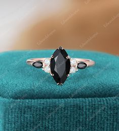 a black and white diamond ring sitting on top of a blue velvet box