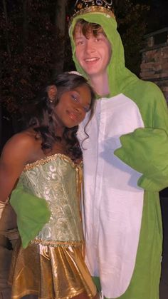 two people dressed up in costumes posing for a photo at an outdoor event, one wearing a frog costume while the other wears a gold dress