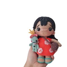 a hand holding a small crocheted doll with an animal on it's arm