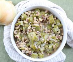 a white bowl filled with food next to an onion on top of a green table