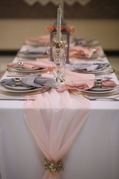 the table is set with silver and pink place settings