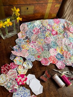 the table is covered with many different pieces of fabric and sewing supplies, along with some yellow flowers