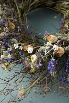 an arrangement of dried flowers and herbs on a blue surface