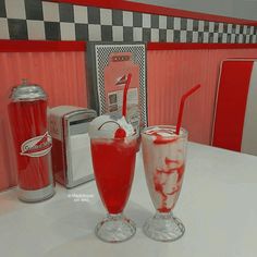 two glasses filled with liquid sitting on top of a table next to a blender