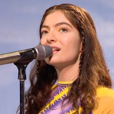 a woman standing in front of a microphone and singing into a microphone with long hair