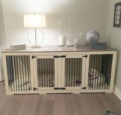 a white dog kennel with doors open and a lamp next to it on top of a wooden floor