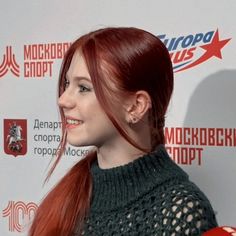 a woman with red hair is smiling and wearing a green sweater on the red carpet