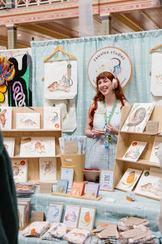 a woman standing in front of a table full of cards and greeting cards for sale