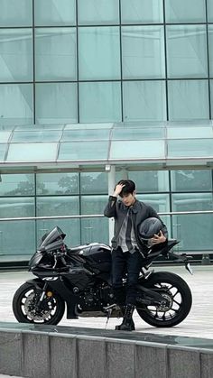 a man standing next to a motorcycle talking on a cell phone in front of a building