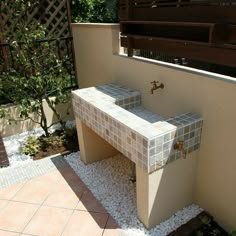 an outdoor sink in the middle of a patio with gravel around it and plants on either side