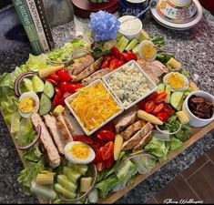 a platter filled with meat, cheese and veggies on top of a table