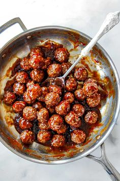 meatballs are being cooked in a skillet with a spatula on the side