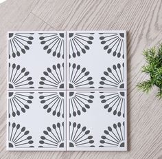 three tiles with black and white designs on them next to a potted green plant