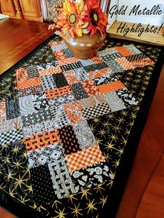 a quilted table runner with sunflowers on it and a sign in the background