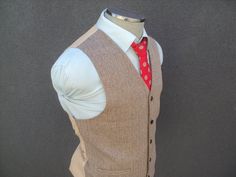 "A custom made brown tweedy wool vest finished in a beautiful herringbone weave. The vest/waistcoat features a five-button front, dual lower front pockets. rayon backing with an adjustable back strap to tighten the fit should it be required. Estimated sizes: 36 Small / 38 Medium / 40 Medium / 42 Large / 44 Large / 46 XL / 48 XL / 50 XXL / 52 XXL (THIS SIZE IS FOR REFERENCE ONLY. PLEASE COMPARE MEASUREMENTS BELOW WITH A WELL FITTING VEST/WAISTCOAT FOR BEST FIT) Brand/Label: Bude Brothers Measurements:  Size 36 Small Armpit to Armpit: 18.50\" Front Length: 25.50\" Size 38 Medium Armpit to Armpit: 19.50\" Front Length: 25.50\" Size 40 Medium Armpit to Armpit: 20.50\" Front Length: 25.50\" Size 42 Large Armpit to Armpit: 21.50\" Front Length: 26.50\" Size 44 Large Armpit to Armpit: 22.50\" Fro Fitted Brown Tweed Three-piece Suit, Fitted Tweed Vest With Herringbone Pattern, Formal Brown Tweed Vest, Brown Notch Lapel Vest For Business, Fitted Brown Wool Vest, Brown Business Vest With Notch Lapel, Tailored Brown Tweed Vest, Brown Semi-formal Vest With Notch Lapel, Brown Notch Lapel Vest For Semi-formal Occasions